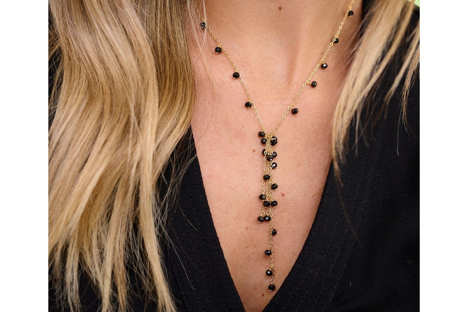 Ivy Black Spinel Lariat Gemstone Necklace styled with a plunging neckline, featuring sleek black spinel gemstones and warm gold accents, ideal for evening glamour.