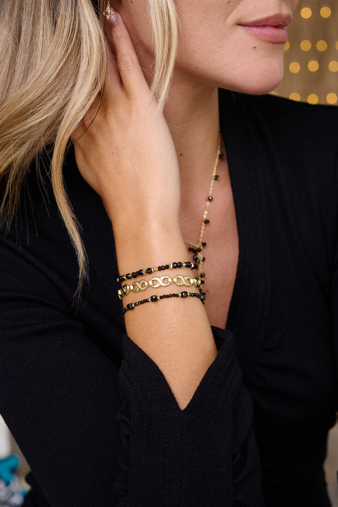 Izu Black Spinel Gold Stacking Bracelet styled on the wrist, showcasing faceted black spinel gemstones and elegant gold chain links for a boho-chic look.