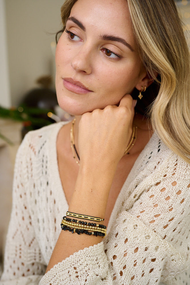 Tahiti Black Spinel Gold Bracelet Stack styled on the wrist, showcasing shimmering black gemstones and luxurious gold accents for a cosmic, boho-chic look.